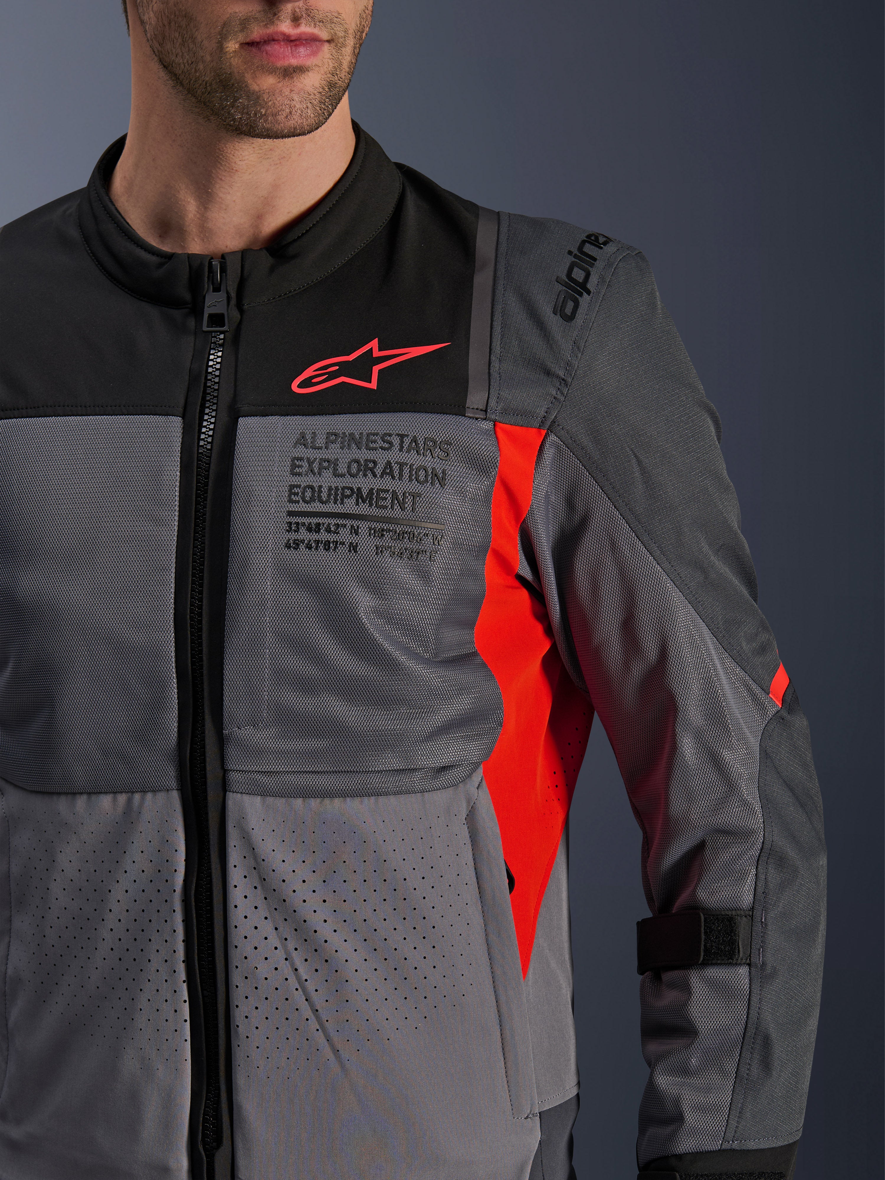 Giacca Alpinestars ST-2 Air, giacca da moto in tessuto, Deep Gray e Dark Gray con dettagli Bright Red, primo piano con pannelli in rete traspirante, tessuto traforato al laser e logo a stella rosso con marchio Alpinestars Exploration Equipment