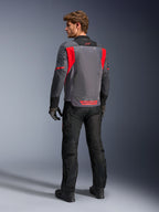 Pilota visto da dietro che indossa la giacca Alpinestars St-2 Air in Deep Gray, Dark Gray e Bright Red, che mette in risalto l'ampio pannello di ventilazione in rete sulla schiena e il logo rosso, abbinata a pantaloni da moto neri e guanti grigi.