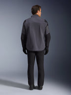 Alpinestars Maxdura Drystar®XF Laminated Armored Shell, giacca da moto, grigio scuro e nero, vista posteriore di un pilota con equipaggiamento adventure completo, guscio laminato tecnico con pannelli neri rinforzati su spalle e gomiti, abbinata a pantaloni e guanti neri.