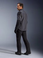 Alpinestars Maxdura Drystar®XF Laminated Armored Shell, giacca da moto adventure, grigio scuro e nero, vista posteriore su modello che guarda oltre la spalla, indossata con pantaloni da moto e stivali neri, design tecnico laminato a 3 strati per prestazioni in ogni condizione atmosferica