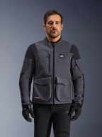 Alpinestars Maxdura Drystar®XF Laminated Armored Shell, giacca da moto adventure in grigio scuro e nero, vista frontale su modello, con ampie tasche cargo, logo 'All Terra' sul petto e cerniere di ventilazione, abbinata a guanti e pantaloni da guida neri.