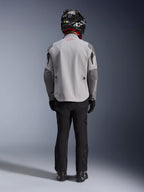 Alpinestars Maxdura Drystar®XF Laminated Armored Shell, giacca da moto grigio medio e grigio scuro, vista dal retro su un pilota, indossata con pantaloni neri, stivali neri e un casco bianco e nero, abbigliamento adventure touring