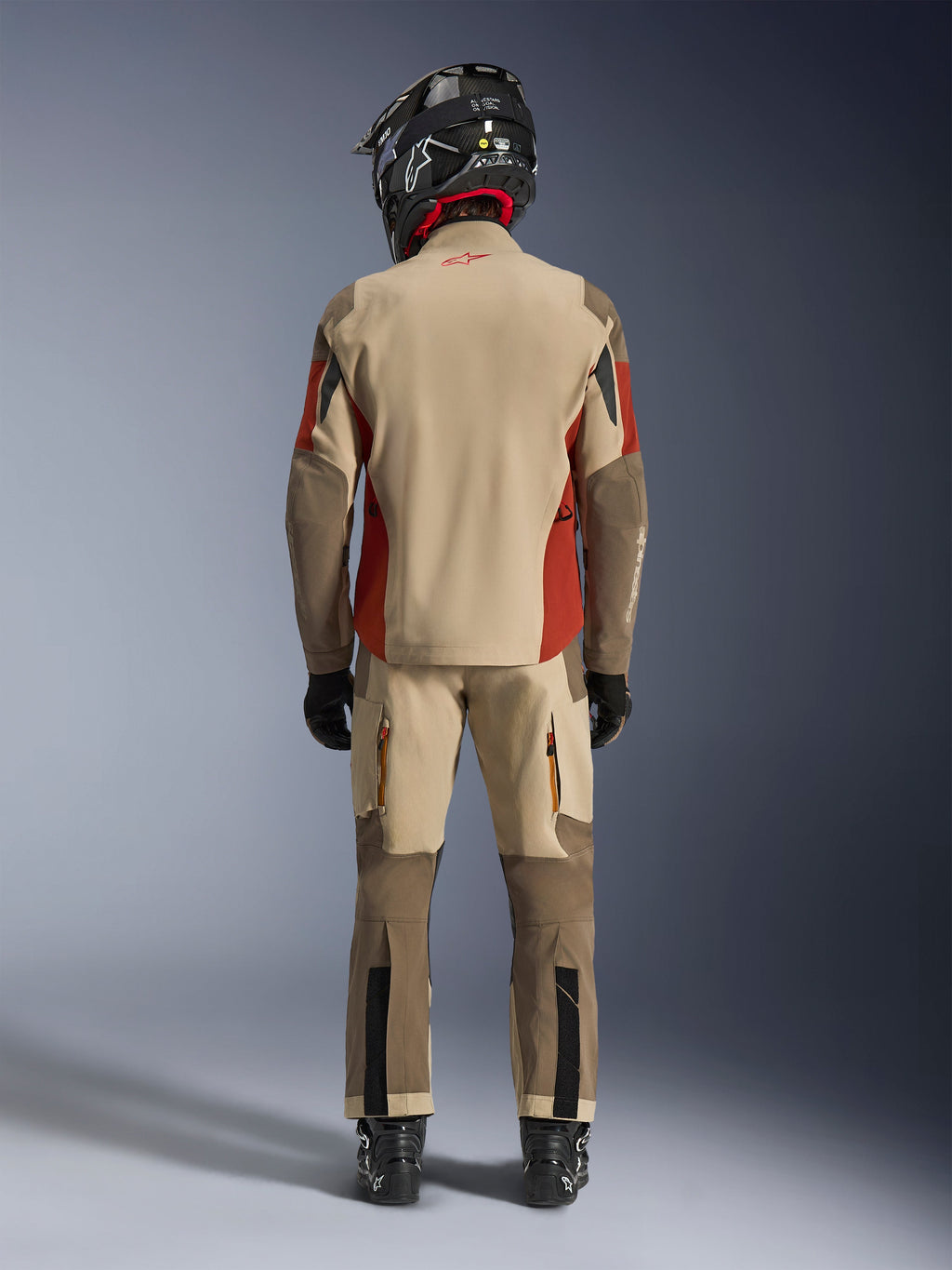 Alpinestars Maxdura Drystar®XF Laminated Armored Shell, giacca da moto adventure e pantaloni coordinati, colorazione Aluminum Walnut e Rust Brown, vista posteriore del pilota con casco e stivali neri, equipaggiamento professionale da adventure-touring