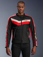 Alpinestars T-Dyno WR Jacket, giacca da moto in tessuto, nera con strisce a chevron rosso acceso ed ecru, vestibilità da biker d'ispirazione vintage, collo alto con chiusura a bottone, tasche anteriori con zip, loghi a stella sulle maniche, indossata da un modello