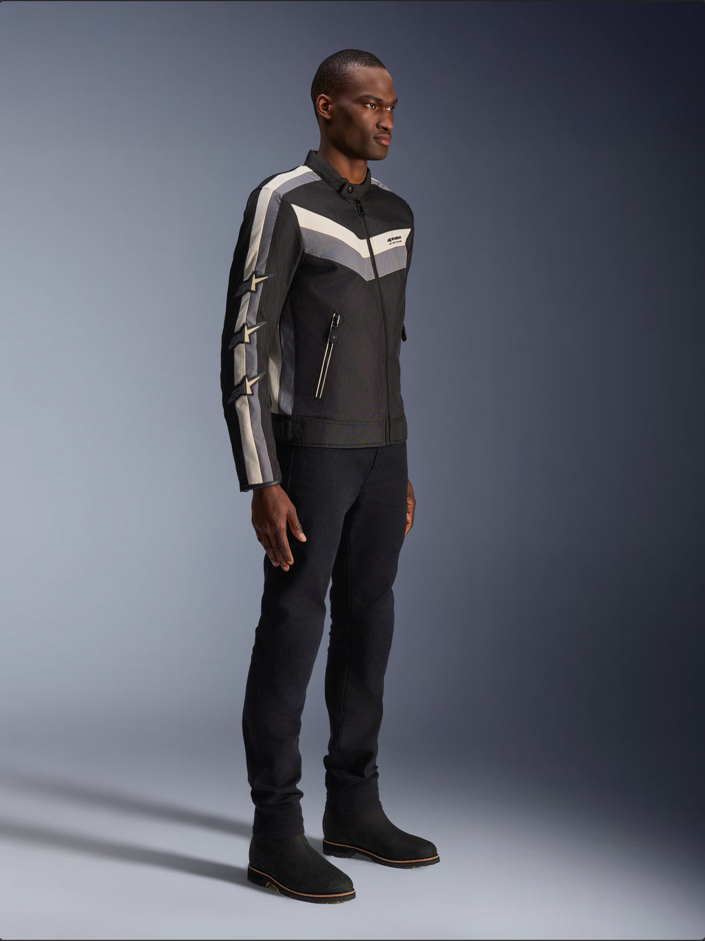 Giacca Alpinestars T-Dyno WR, giacca da moto in tessuto, nera con dettagli a gallone grigio scuro ed ecru, vestibilità biker d'ispirazione vintage, indossata con pantaloni e stivali neri per un look da strada completo