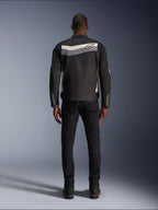 Giacca Alpinestars T-Dyno WR, giacca da moto in tessuto, nero, grigio scuro ed ecru, vista posteriore con striscia orizzontale sulle spalle e piccolo logo a stella, indossata da un modello con pantaloni e stivali neri, abbigliamento tecnico d'ispirazione vintage