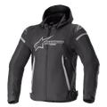 Alpinestars Zaca Waterproof Jacket, giacca sportiva da moto, nero e grigio scuro, dotata di cappuccio rimovibile, grande logo grigio sul petto, dettagli grigio chiaro su spalle e fianchi, cinghie regolabili in vita, chiusura frontale con zip, struttura sportiva in tessuto