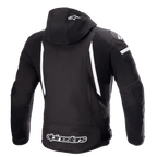 Alpinestars Zaca Waterproof Jacket, giacca da moto, nero e bianco, vista posteriore con cappuccio rimovibile e logo a stella bianco, strisce bianche verticali sul retro, marchio Alpinestars sul bordo inferiore e pannelli elasticizzati a costine per la mobilità.