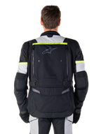 Giacca Alpinestars Bogotá Pro Drystar®, giacca da moto adventure touring, nero, grigio ghiaccio e giallo fluo, vista posteriore con branding 'TECH TOURING' su una striscia giallo fluorescente, ampio pannello di ventilazione posteriore e cinturini di regolazione in vita, abbigliamento tecnico per tutte le stagioni