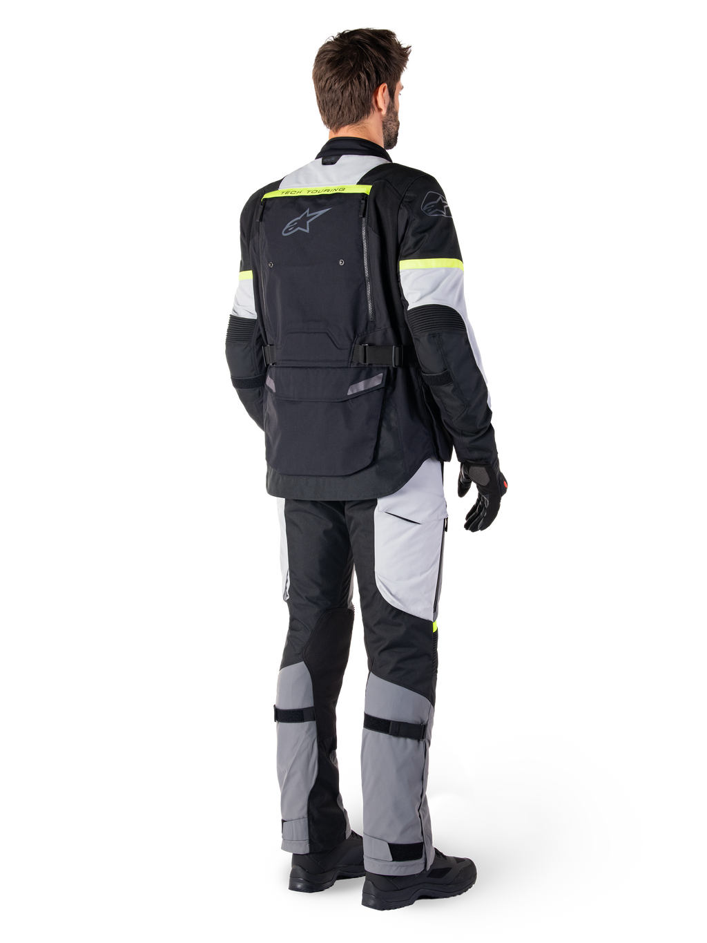 Vista posteriore di un pilota che indossa la giacca Alpinestars Bogotá Pro Drystar® in Black Ice Gray Yellow Fluo, abbinata a pantaloni adventure touring coordinati, dotata di un'ampia tasca posteriore e accenti giallo fluorescente, equipaggiamento tessile da moto per tutte le stagioni.