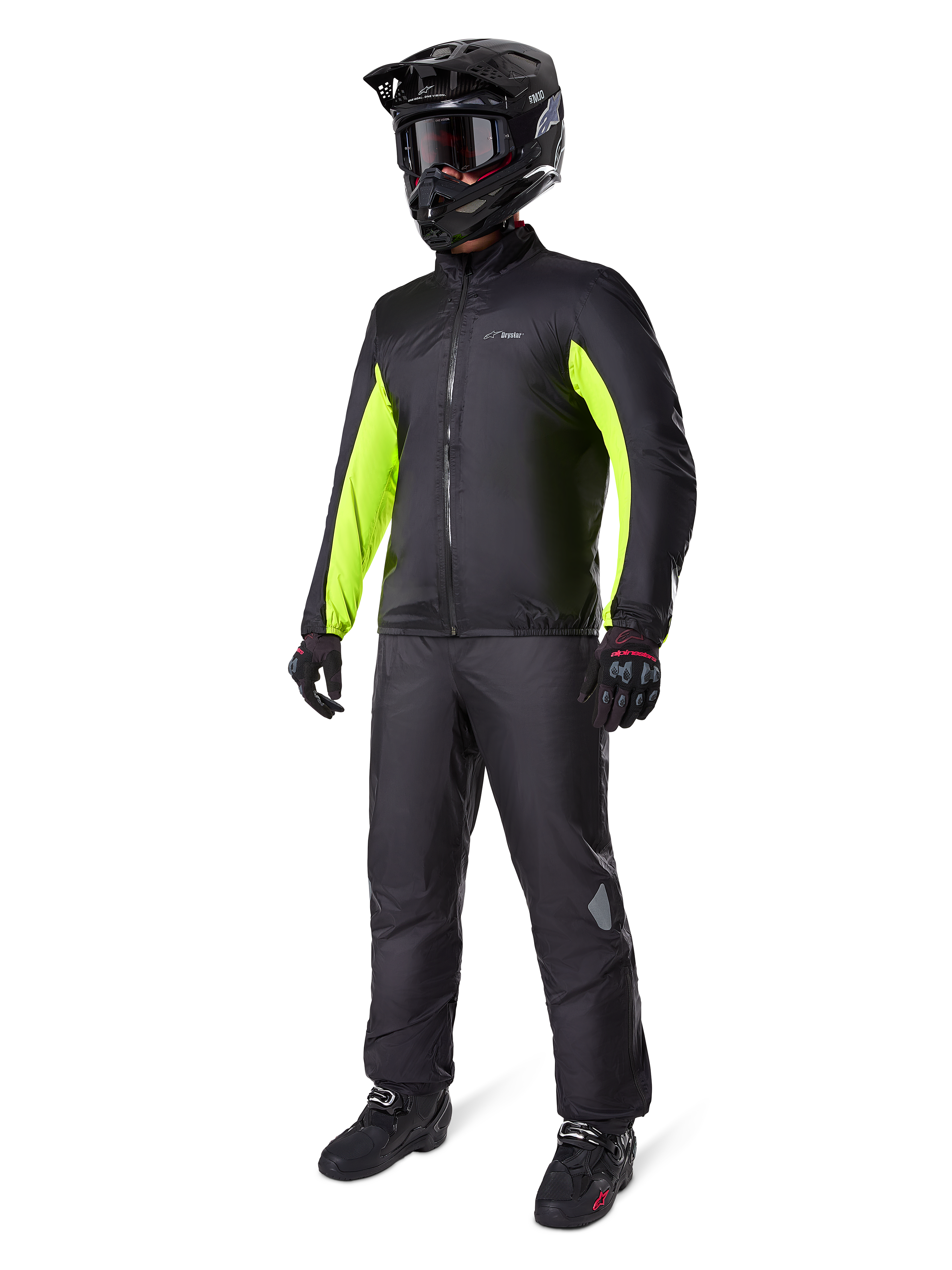 Motociclista che indossa la fodera della giacca Alpinestars Bogotá Pro Drystar®, nera con pannelli giallo fluo vivaci sulle maniche, abbinata a pantaloni neri coordinati, casco da motocross nero e guanti, equipaggiamento adventure impermeabile per tutte le stagioni