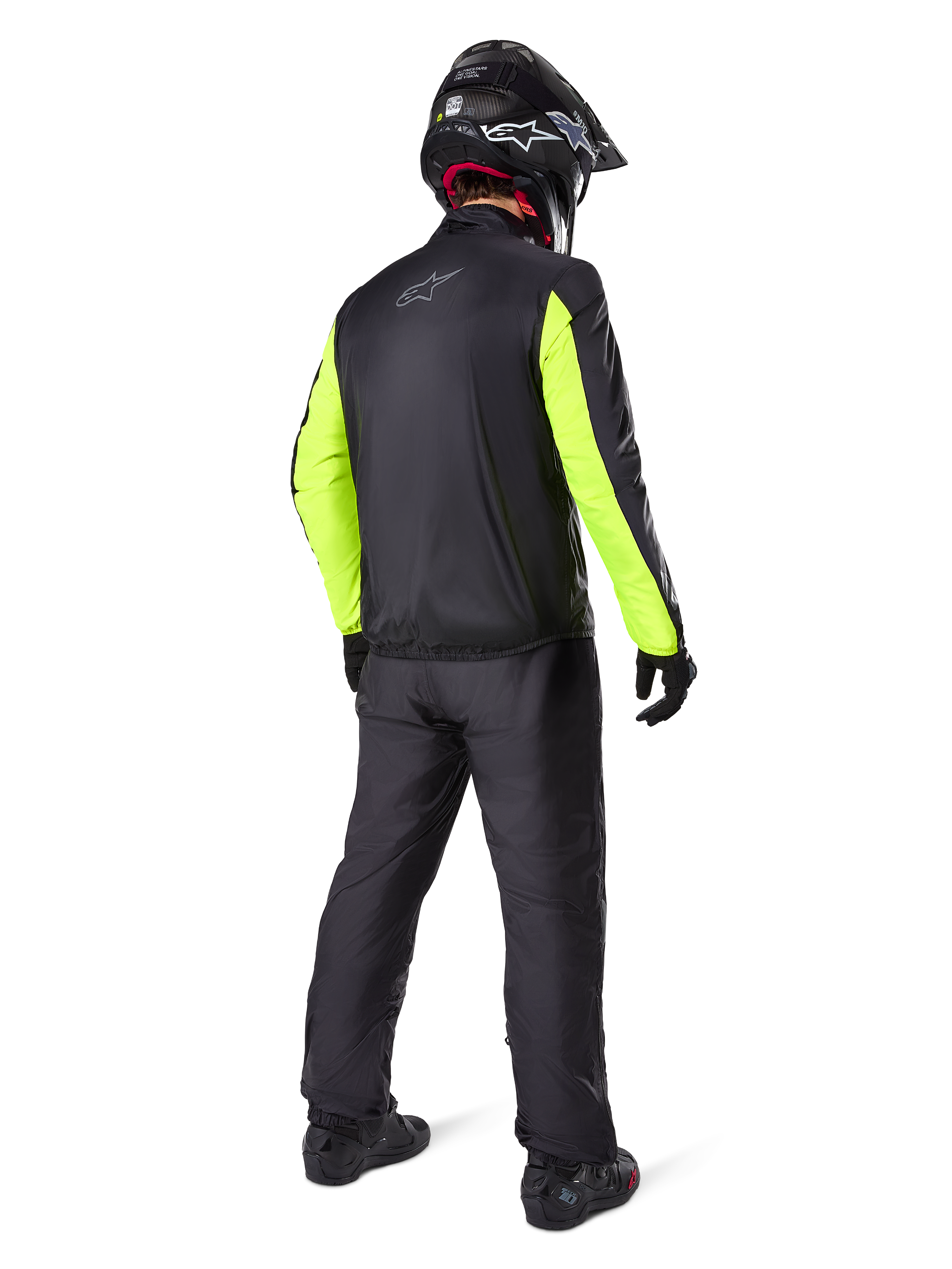 Motociclista visto di spalle con la giacca Alpinestars Bogotá Pro Drystar®, nera con maniche giallo fluo brillante, pantaloni e casco neri coordinati, abbigliamento tecnico adventure per tutte le stagioni