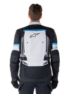 Giacca Alpinestars Bogotá Pro Drystar®, giacca da moto Adventure, Ice Gray Black e Cyan, vista posteriore con un ampio pannello grigio chiaro e logo a stella nero, accenti ciano con marchio Tech Touring e cinghie regolabili in vita