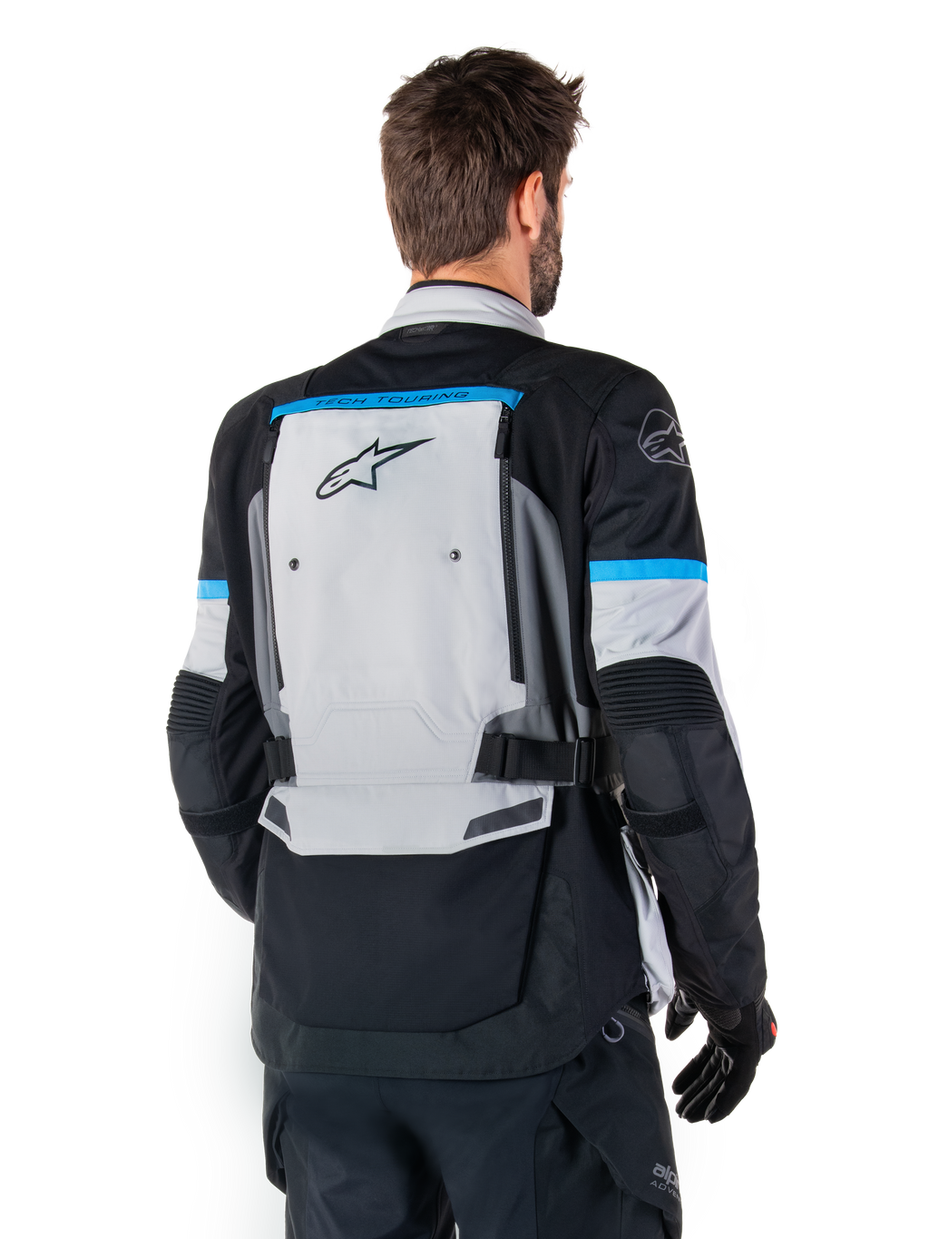Giacca Alpinestars Bogotá Pro Drystar®, giacca da moto adventure, Ice Gray, nero e ciano, vista posteriore con ampio pannello grigio e marchio Tech Touring, dettagli ciano sulle maniche e struttura in tessuto resistente.