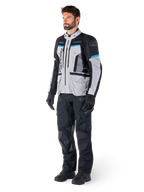 Pilota uomo che indossa la giacca Alpinestars Bogotá Pro Drystar® in Ice Gray, Black e Cyan, abbinata a pantaloni tecnici da guida e guanti neri, equipaggiamento adventure touring per prestazioni in ogni condizione atmosferica.