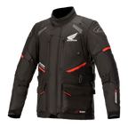 Giacca Honda Andes V3 Drystar, giacca moto touring, nera con dettagli rossi, vista frontale con grandi tasche cargo e cinghie regolabili, costruzione in tessuto tecnico con loghi Honda e Alpinestars, design di ispirazione adventure