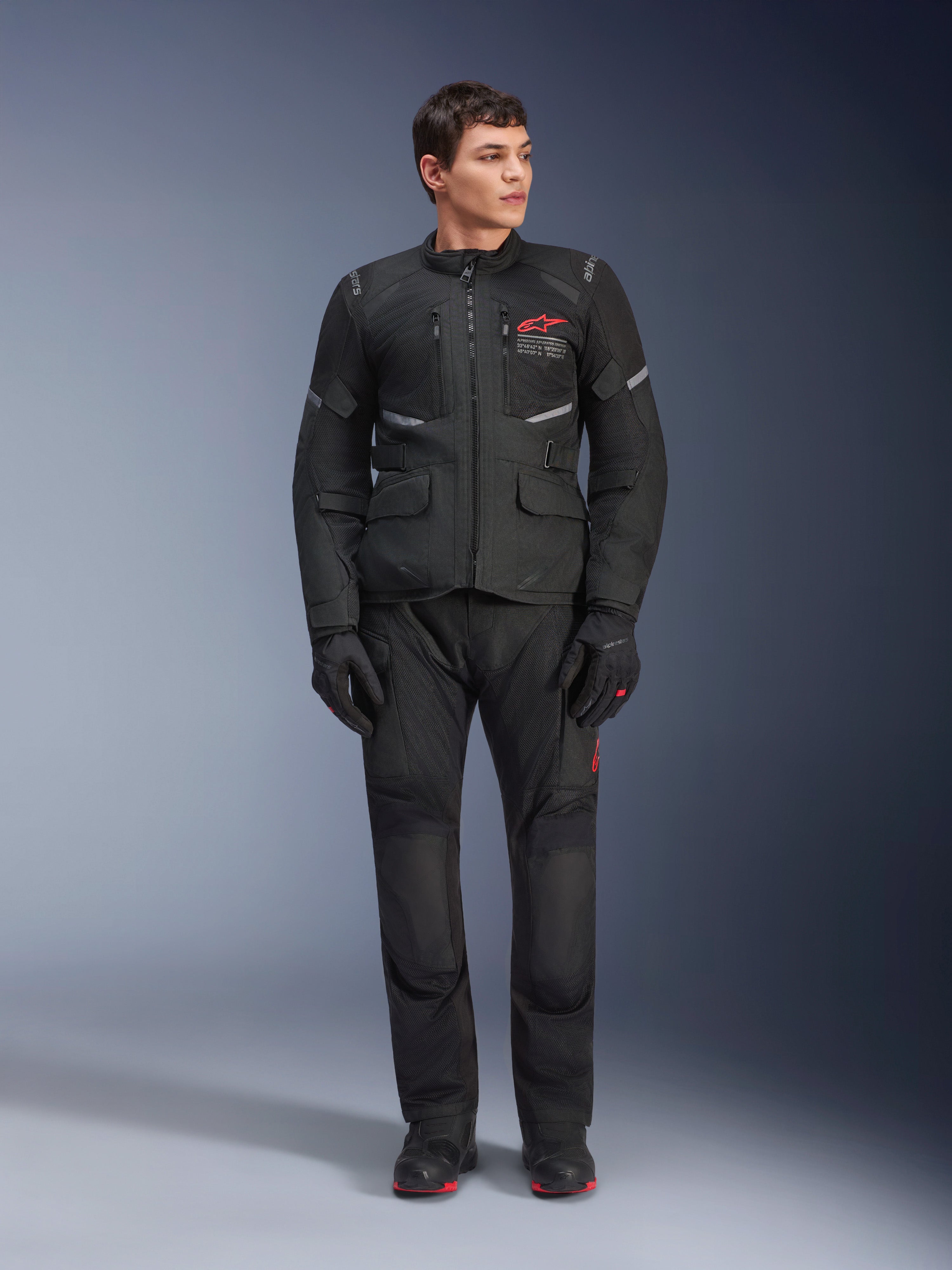 Alpinestars Andes Air Drystar® Pants, pantaloni da moto touring, nero, con pannelli di ventilazione in rete e logo rosso sulla gamba, indossati come parte di un completo da guida con giacca e guanti coordinati, equipaggiamento professionale per adventure touring
