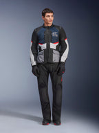 Giacca Alpinestars Andes Air Drystar®, giacca da moto touring, blu scuro, nero e grigio ghiaccio, indossata con pantaloni e guanti adventure neri coordinati, con pannelli in mesh per il flusso d'aria e un design tecnico multitasche.