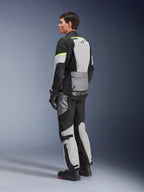 Giacca Alpinestars Andes Air Drystar®, giacca da moto touring, grigio ghiaccio e grigio scuro con pannelli neri e accenti giallo neon, indossata con pantaloni e guanti coordinati, vista posteriore di tre quarti che mostra la ventilazione in rete e il marchio Alpinestars.