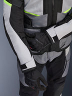 Giacca Alpinestars Andes Air Drystar®, giacca da mototurismo, grigio ghiaccio e grigio scuro con dettagli giallo neon, primo piano che mostra i pannelli in rete e le cinghie di regolazione, indossata con guanti Alpinestars neri