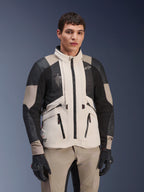Giacca Alpinestars AMT-10LAB Drystar® XF, White Sand Aluminum Camo, giacca da moto adventure con pannelli in mesh MATRYX® neri e rinforzi in pelle, indossata da un modello con guanti neri e pantaloni coordinati color sabbia, ritratto in studio