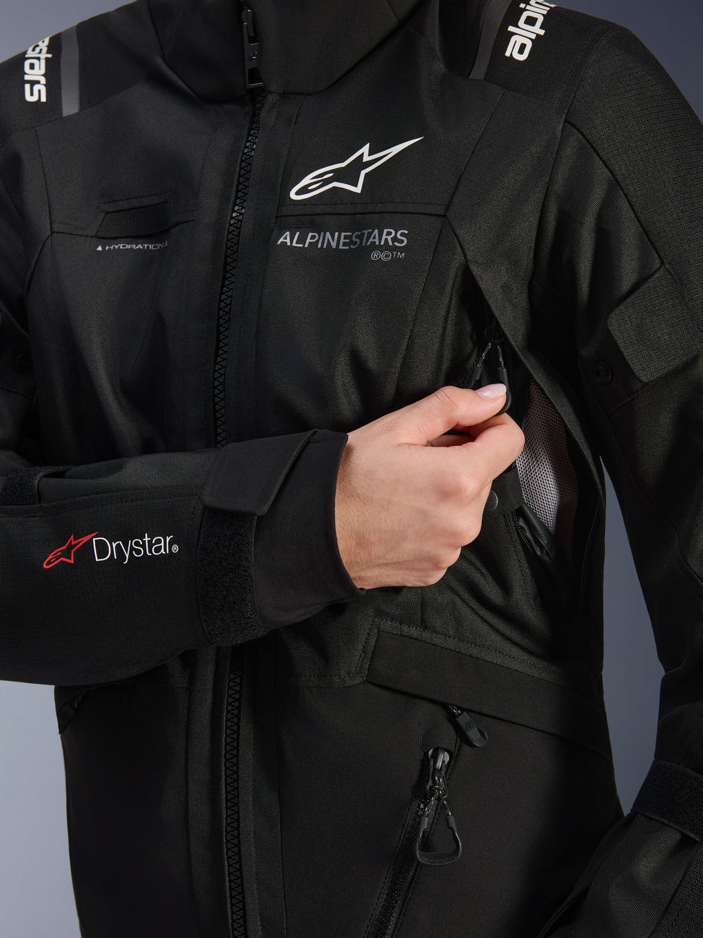 Giacca donna Alpinestars Stella Andes V4 Drystar®, nera, dettaglio della presa di ventilazione sul petto in fase di apertura con fodera in mesh, logo Drystar® sull'avambraccio e asola per il tubo di idratazione, abbigliamento tecnico da moto