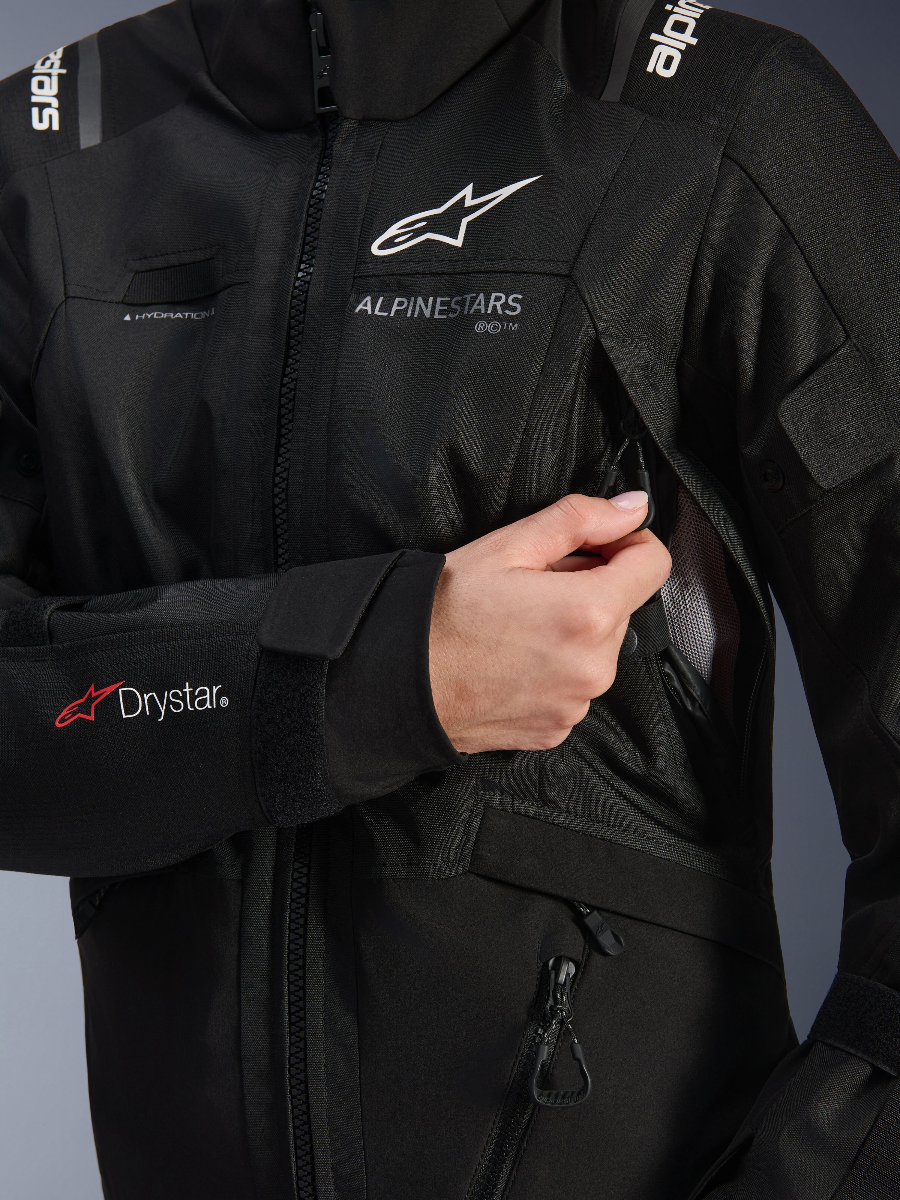 Giacca donna Alpinestars Stella Andes V4 Drystar®, nera, dettaglio della presa di ventilazione sul petto in fase di apertura con fodera in mesh, logo Drystar® sull'avambraccio e asola per il tubo di idratazione, abbigliamento tecnico da moto