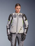 Giacca da donna Alpinestars Stella Andes V4 Drystar®, grigio ghiaccio e grigio scuro con accenti giallo fluo, giacca da moto adventure touring, indossata con pantaloni e guanti abbinati, caratterizzata da una costruzione tessile protettiva e branding Alpinestars.