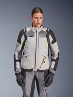 Giacca da donna Alpinestars Stella Andes V4 Drystar®, grigio ghiaccio e grigio scuro con accenti giallo fluo, giacca da moto adventure touring, indossata con pantaloni e guanti abbinati, caratterizzata da una costruzione tessile protettiva e branding Alpinestars.