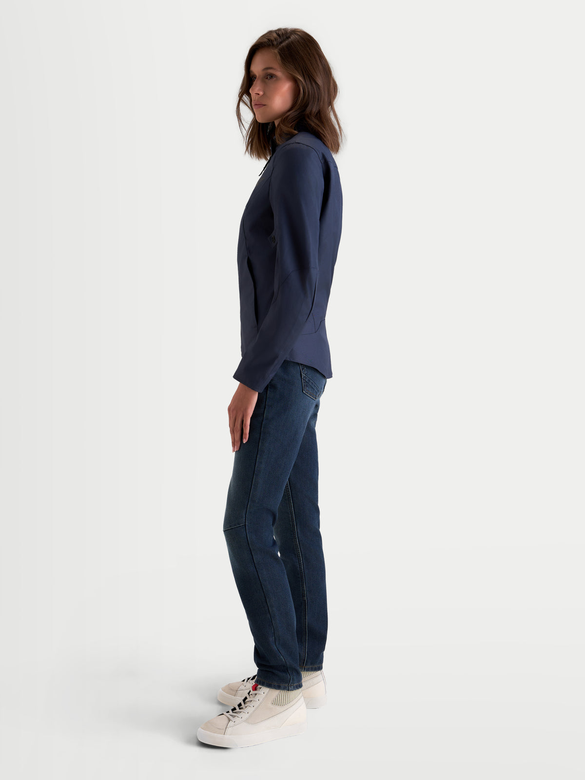 Alpinestars Stella C-1 Waterproof Giacca, giacca da moto urbana da donna in blu indigo, vista di profilo laterale indossata da una modella con jeans e scarpe casual, che mette in mostra la struttura in tessuto impermeabile e la vestibilità ergonomica