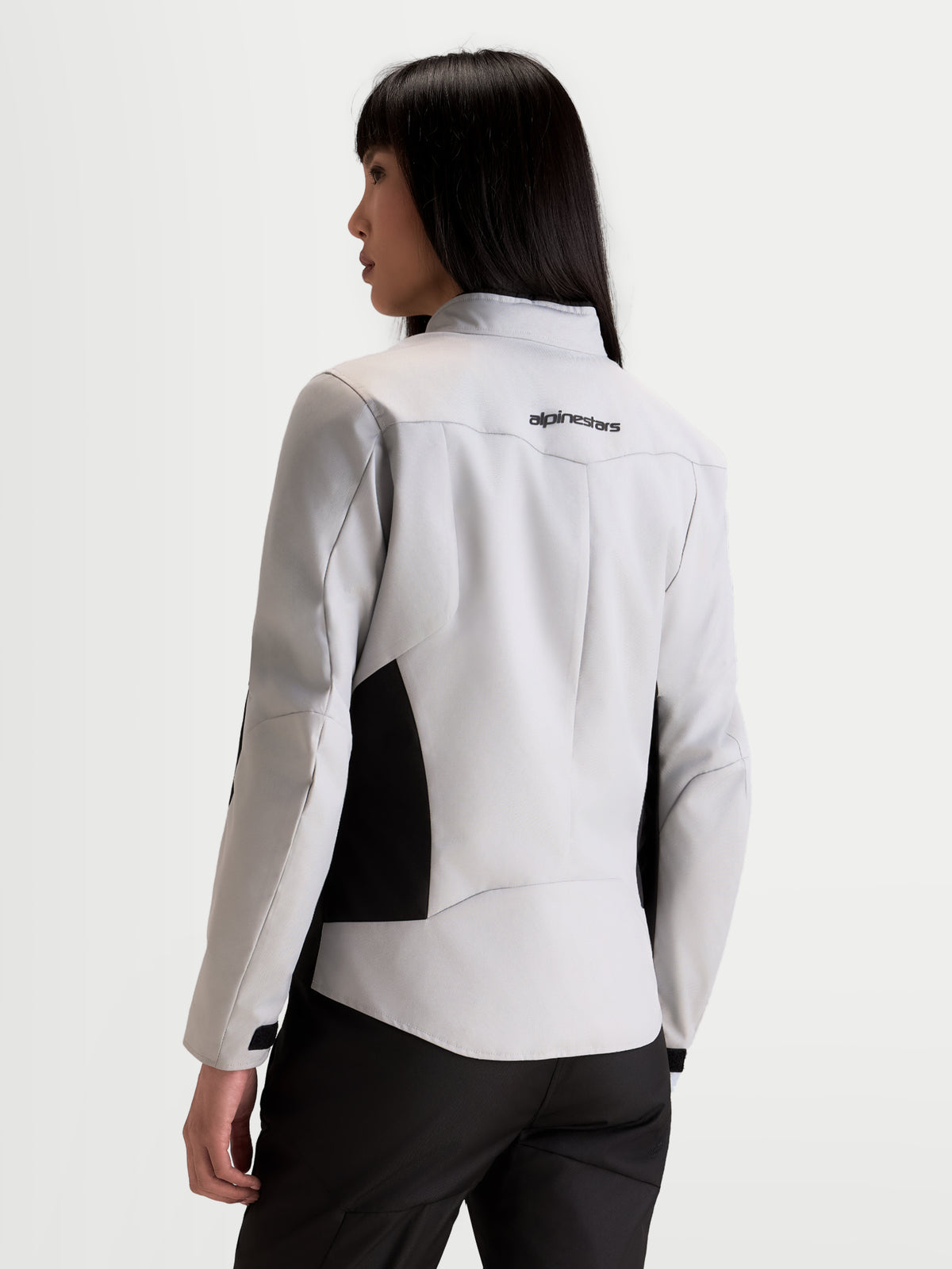Alpinestars Stella C-1 Waterproof Giacca, giacca da moto urbana da donna in grigio ghiaccio e nero, vista posteriore su una modella che mostra la struttura posteriore e il logo del marchio sulla parte superiore della schiena