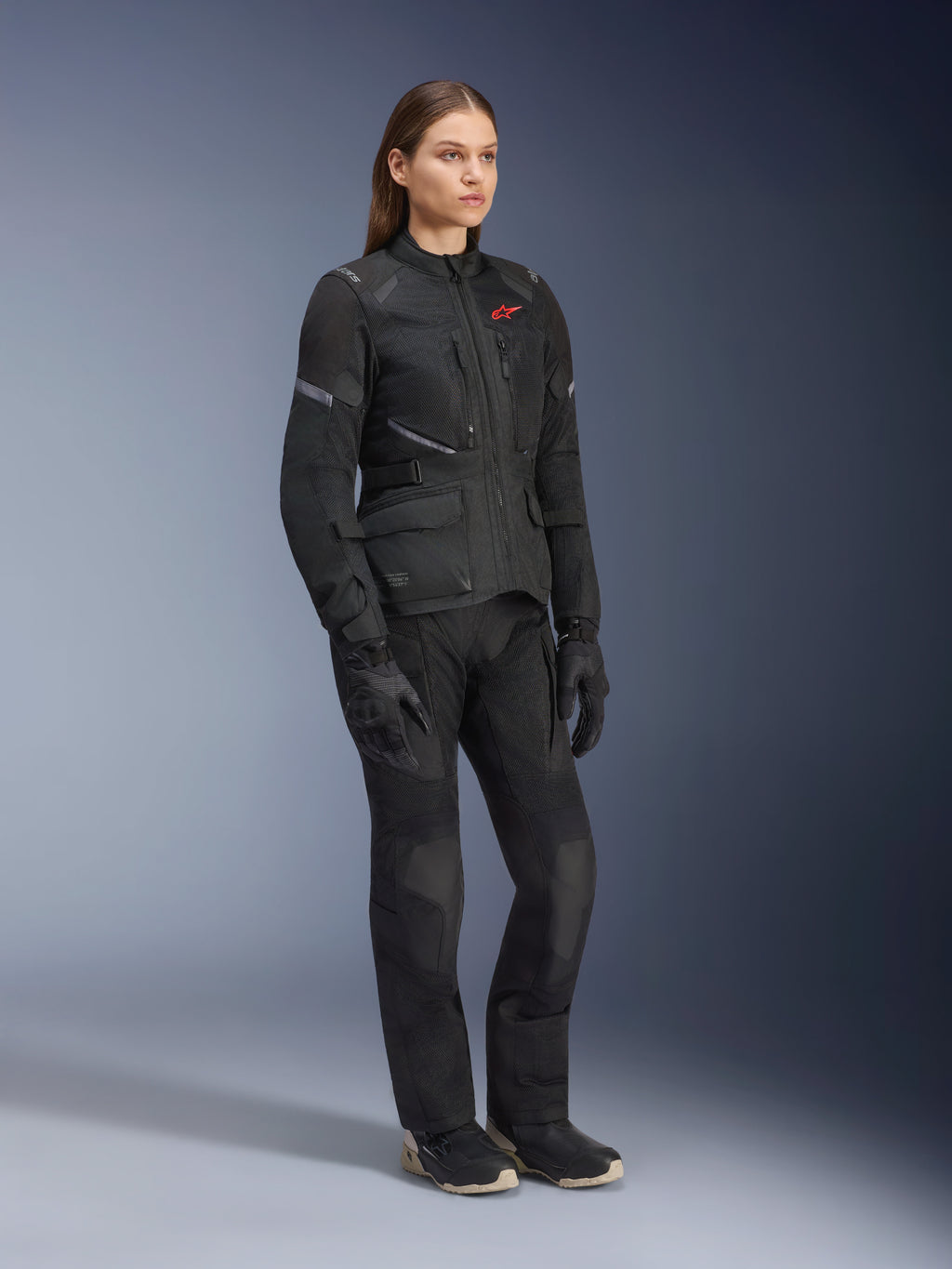 Donna che indossa la giacca Alpinestars Stella Andes Air Drystar®, giacca da touring adventure in tessuto nero, abbinata a pantaloni e guanti neri coordinati, con ampi pannelli di ventilazione in rete e logo rosso, completo coordinato per il motociclismo femminile