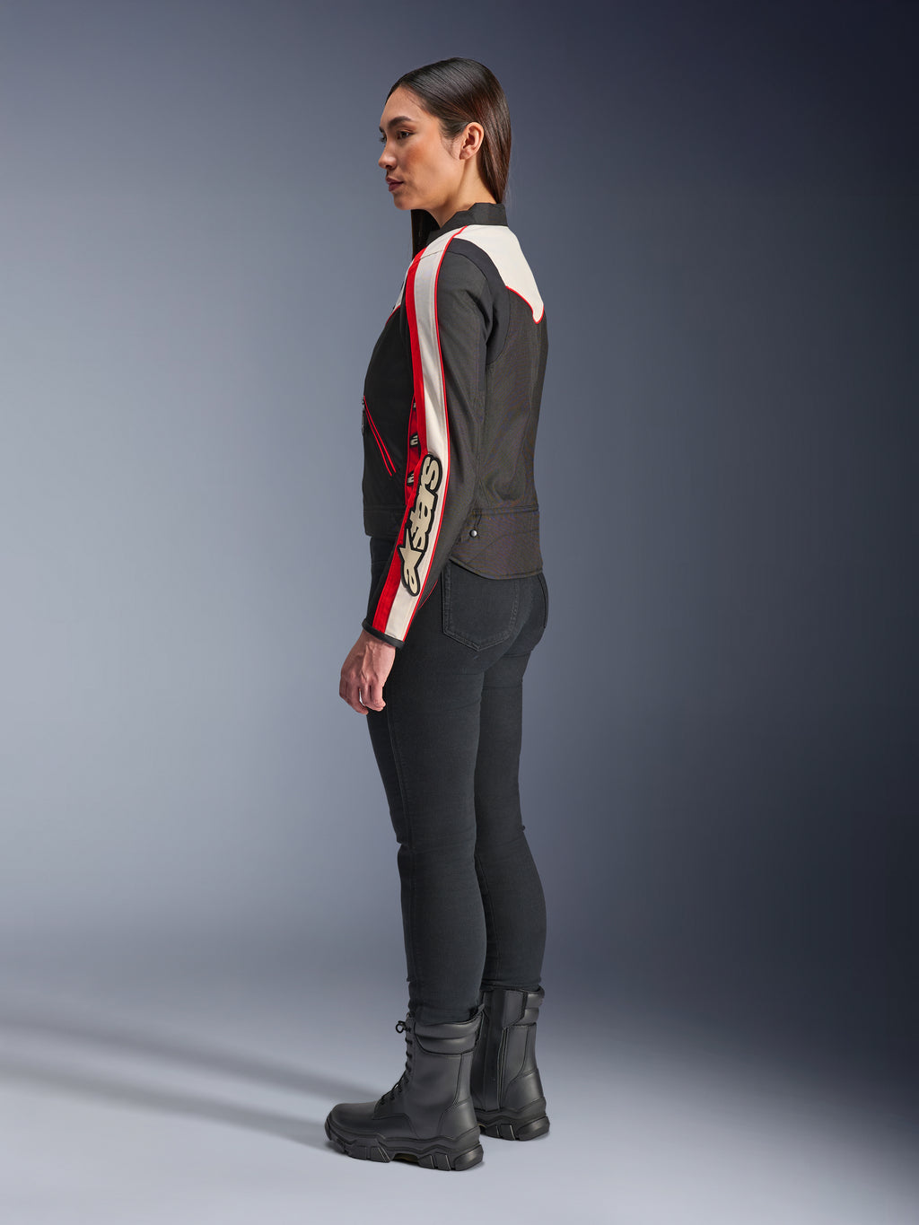 Giacca Alpinestars Stella T-Dyno WR, giacca da moto in tessuto per donna, nero ecru e rosso vivace, design di ispirazione vintage con logo Astars sulla manica, indossata con pantaloni neri slim e stivali neri, vestibilità corta da biker per la guida urbana