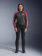 Giacca Alpinestars Stella T-Dyno WR, giacca in tessuto stile vintage, nero con accenti rosso brillante e fucsia, logo rosa e strisce sulle maniche, indossata con pantaloni neri e stivali stringati, abbigliamento da moto urban