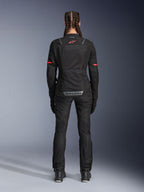 Giacca Alpinestars Stella ST-2 Air, giacca da moto da donna, nero, vista posteriore con logo rosso sulla parte superiore della schiena e marchio grigio sulla parte inferiore della schiena, indossata con pantaloni e stivali da moto neri coordinati, design touring moderno con pannelli in mesh e dettagli riflettenti