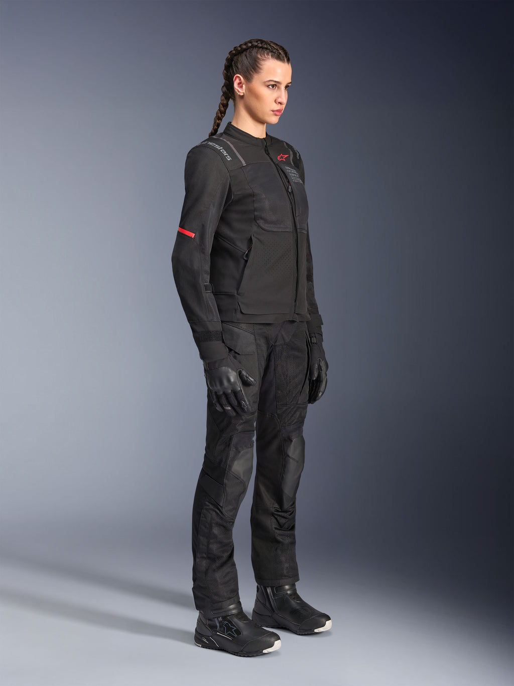 Pilota donna che indossa i pantaloni Alpinestars Stella Andes Air Drystar® in nero, pantaloni adventure in tessuto con pannelli di ventilazione in rete, abbinati a giacca Stella, guanti e stivali coordinati per un outfit completo da mototurismo.