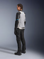 Giacca Alpinestars Stella ST-2 Air in Ice Gray e Nero indossata da una pilota, vista posteriore di tre quarti che evidenzia l'ampio pannello posteriore in mesh grigio chiaro, le maniche nere con dettaglio blu e il logo Alpinestars blu, abbinata a pantaloni, guanti e stivali neri per un outfit completo da adventure touring