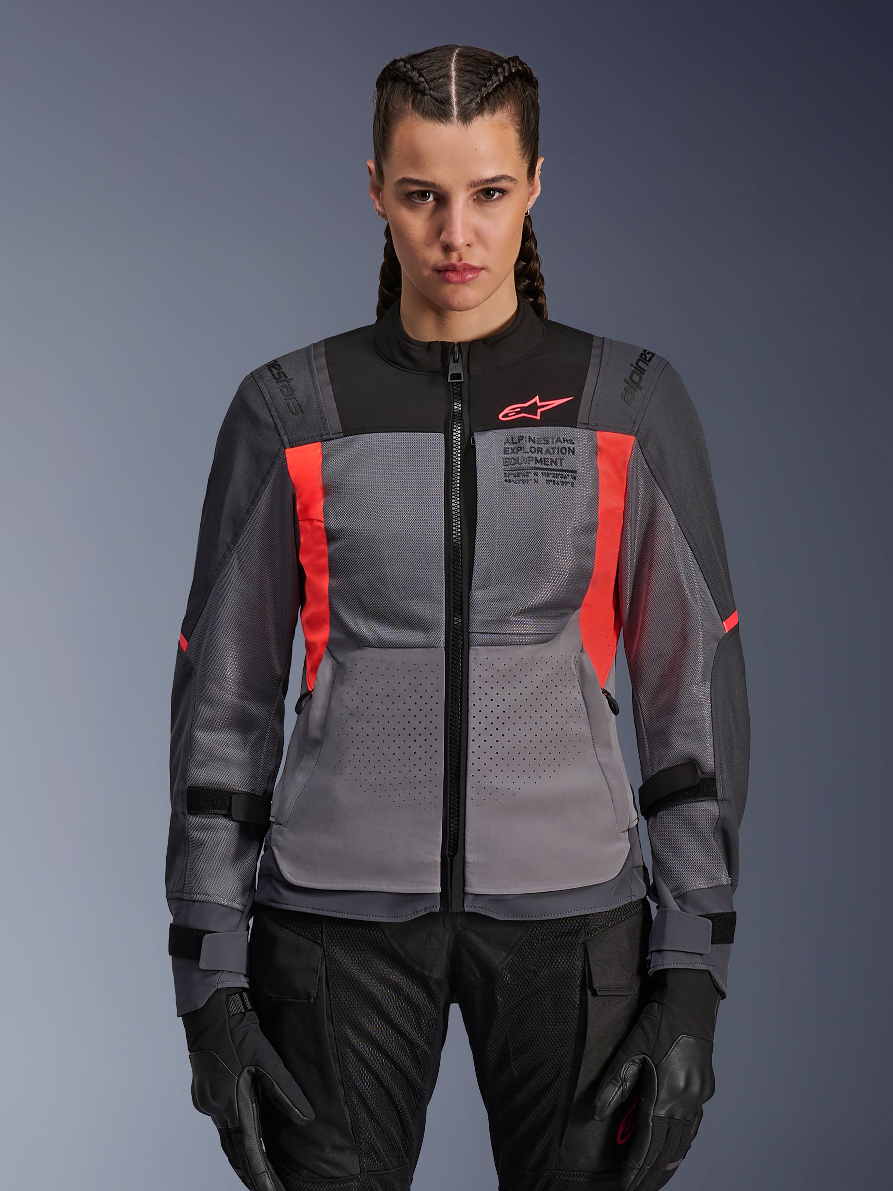 Alpinestars Stella ST-2 Air Jacket, giacca da moto da donna, grigio scuro e corallo fluo, modella che indossa la giacca in tessuto ventilato con pannelli in mesh, accenti corallo acceso e marchio sul petto, stile adventure riding moderno