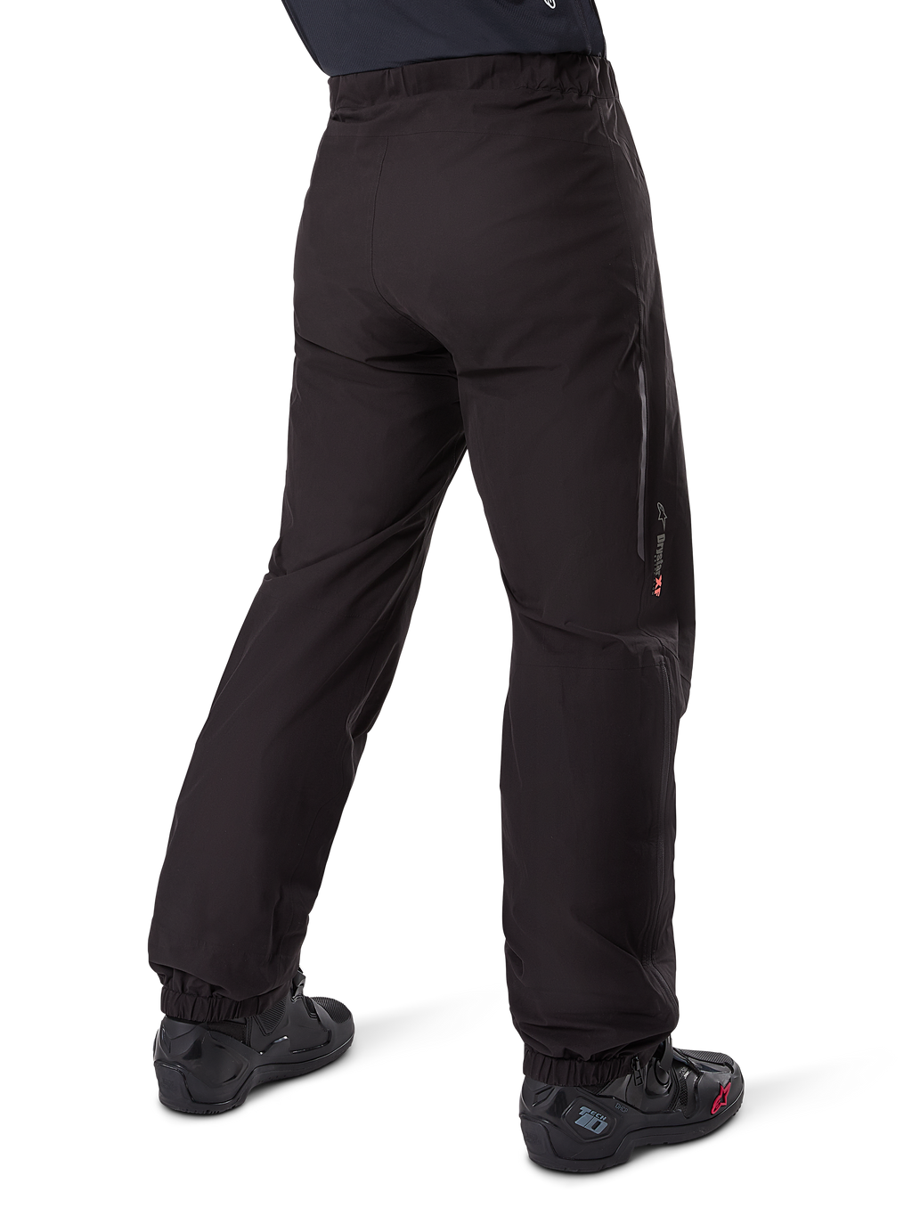 Alpinestars Amt-8 Stretch Drystar® XF Pant Liner, nero, vista posteriore della fodera impermeabile indossata sopra stivali da moto neri, con marchio Drystar XF sulla parte inferiore della gamba, polsini elasticizzati e materiale elasticizzato leggero per adventure touring.
