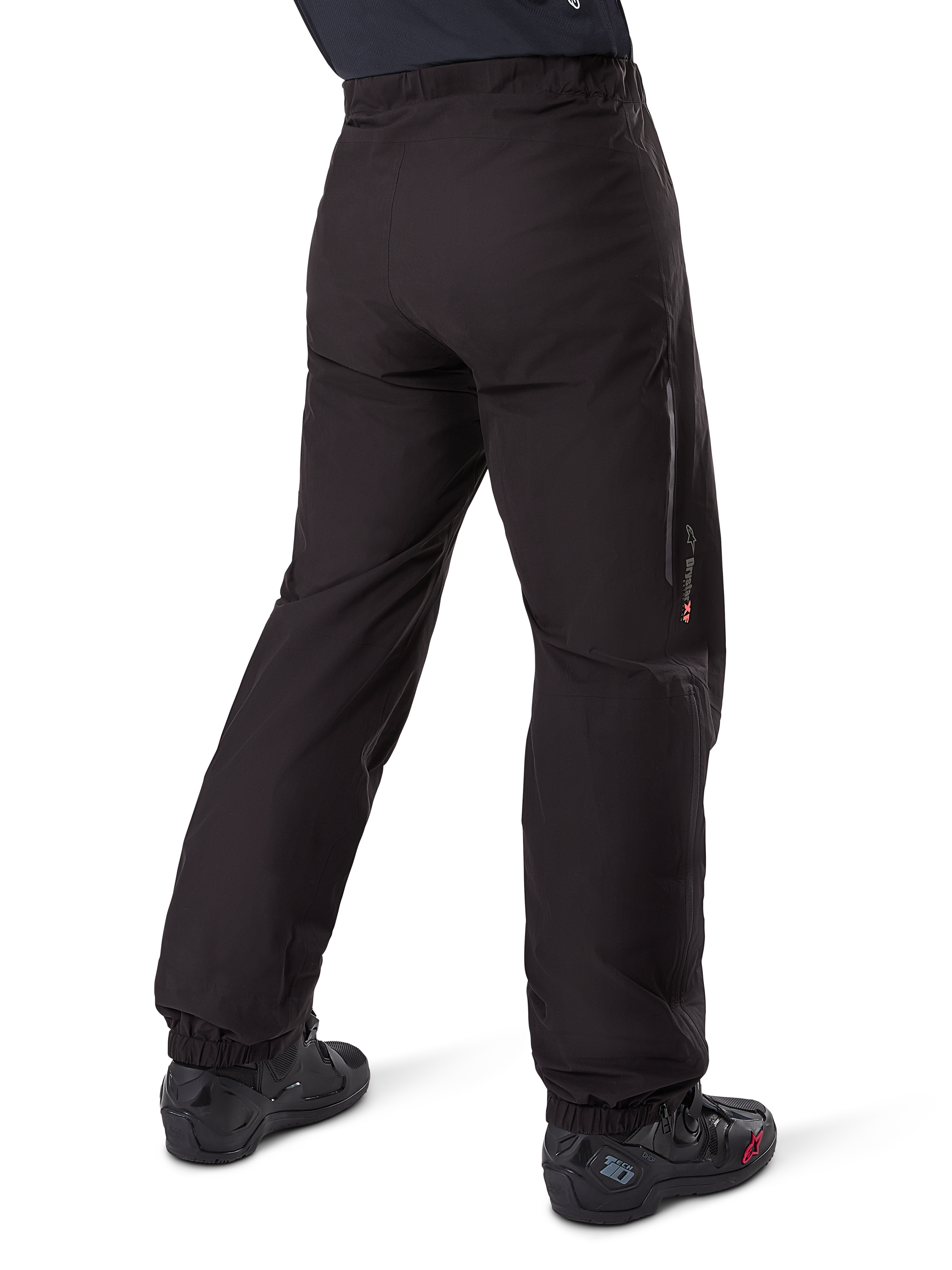 Alpinestars Amt-8 Stretch Drystar® XF Pant Liner, nero, vista posteriore della fodera impermeabile indossata sopra stivali da moto neri, con marchio Drystar XF sulla parte inferiore della gamba, polsini elasticizzati e materiale elasticizzato leggero per adventure touring.