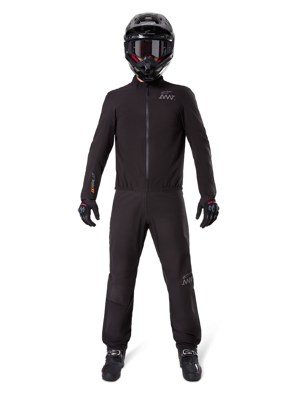 Motociclista che indossa la fodera per pantaloni Alpinestars AMT-8 Stretch Drystar® XF e la giacca coordinata, abbigliamento tecnico completamente nero impermeabile e antivento, con casco, guanti e stivali neri, design elegante per adventure touring.