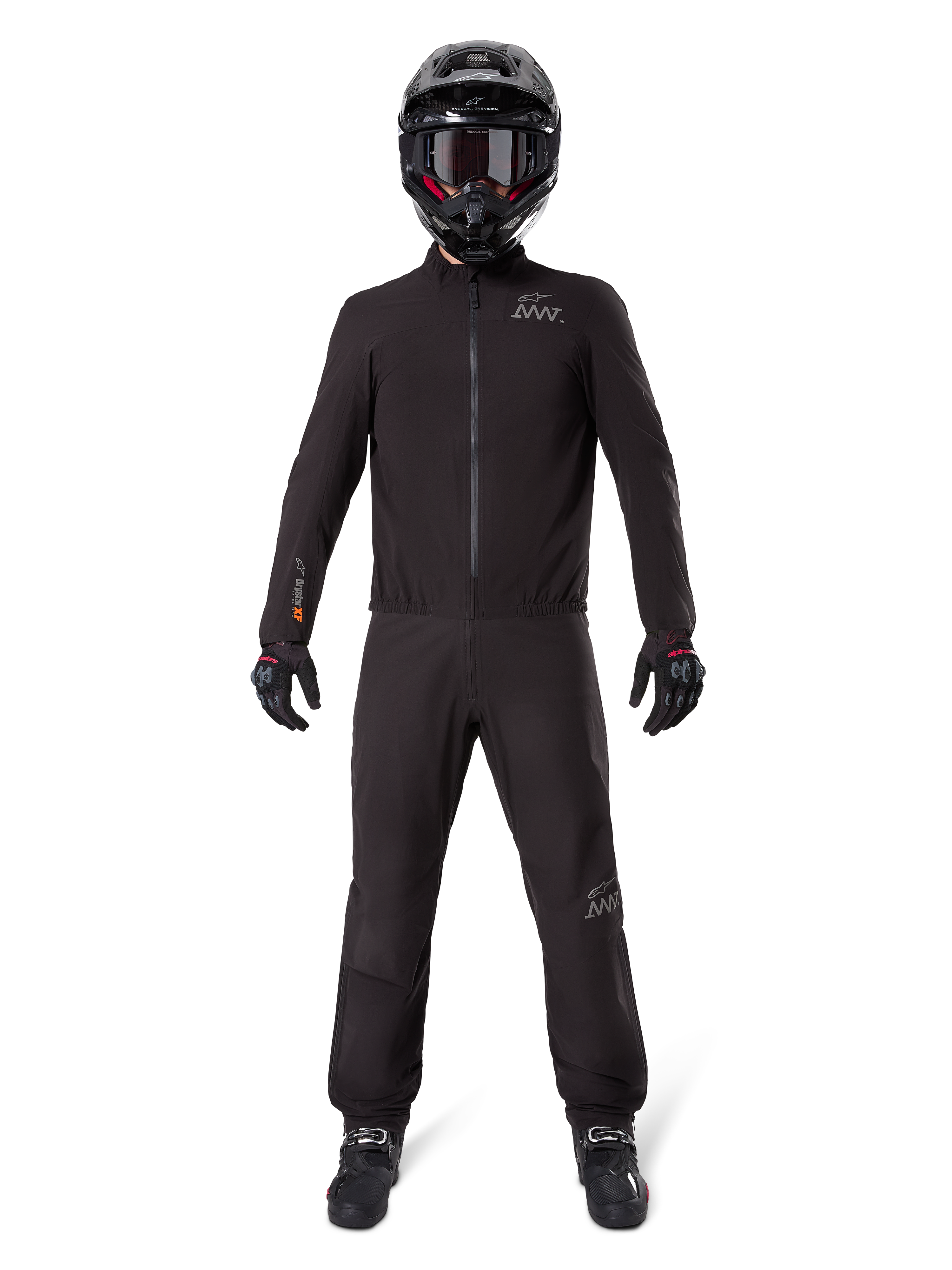 Motociclista che indossa la fodera per pantaloni Alpinestars AMT-8 Stretch Drystar® XF e la giacca coordinata, abbigliamento tecnico completamente nero impermeabile e antivento, con casco, guanti e stivali neri, design elegante per adventure touring.