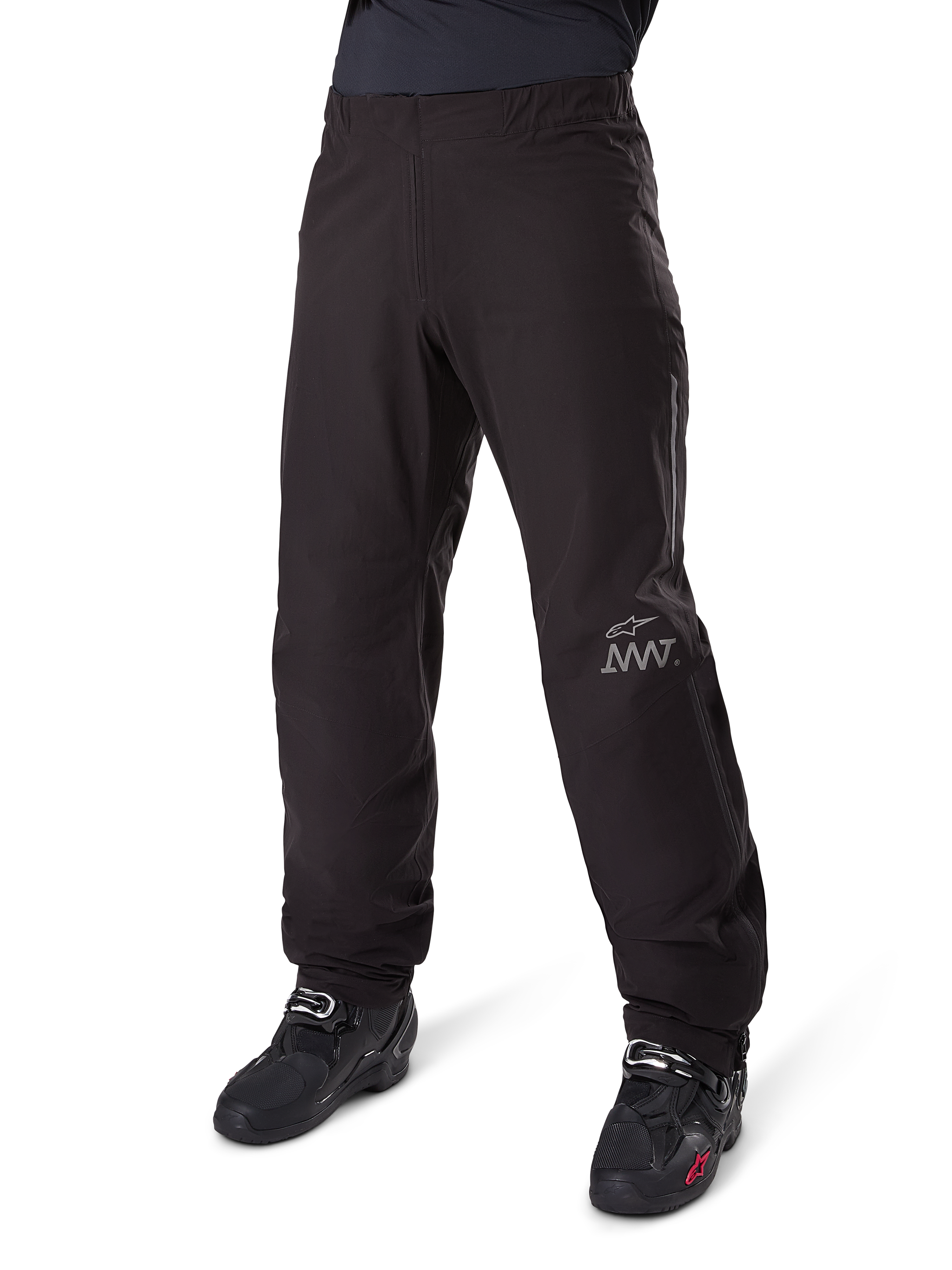 Fodera per pantaloni Alpinestars Amt-8 Stretch Drystar® XF, nero, costruzione in tessuto tecnico impermeabile ed elasticizzato con logo AMT argento, indossata con stivali da moto neri, componente per abbigliamento moto adventure touring.