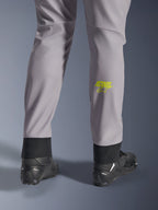 Pantaloni Alpinestars Aeroshell, grigio medio con logo Astars giallo fluo sul polpaccio, vista posteriore con scarpe da moto nere, caratterizzati da orlo inferiore elastico e silhouette moderna affusolata