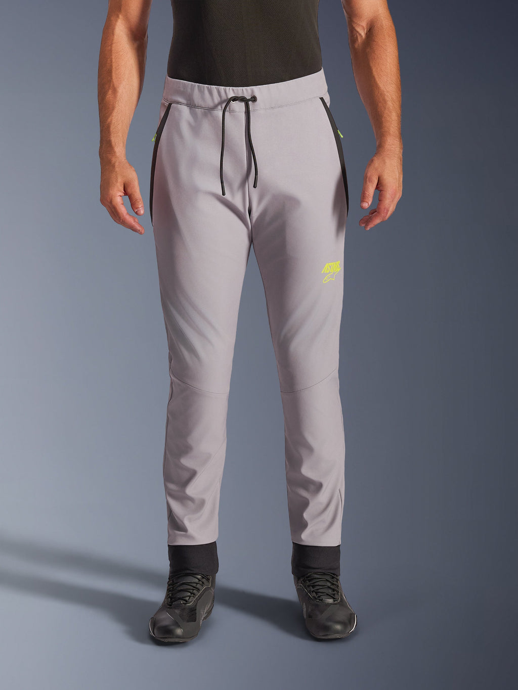 Alpinestars Aeroshell Pants, grigio medio e giallo fluo, pantaloni da moto crossover in softshell, con vita con coulisse nera e polsini alle caviglie, logo giallo sulla coscia sinistra, ginocchia pre-curvate, silhouette sportiva stile jogger