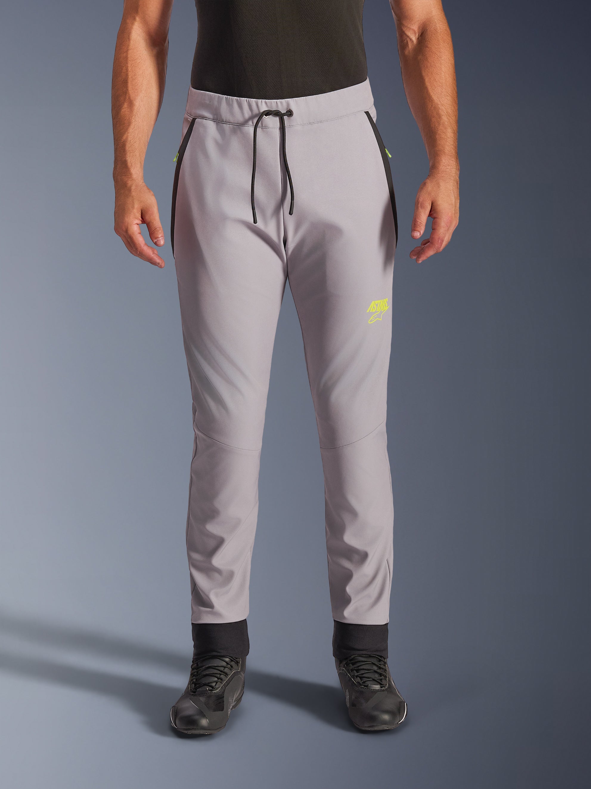 Alpinestars Aeroshell Pants, grigio medio e giallo fluo, pantaloni da moto crossover in softshell, con vita con coulisse nera e polsini alle caviglie, logo giallo sulla coscia sinistra, ginocchia pre-curvate, silhouette sportiva stile jogger