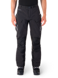 Pantaloni Alpinestars Hyde XT Drystar, pantaloni adventure touring neri, indossati da un pilota con stivali neri, con loghi grigi sulle cosce, cintura integrata, pannelli rinforzati sulle ginocchia e costruzione in tessuto impermeabile