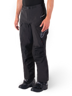 Alpinestars Hyde XT Drystar® Pants, pantaloni da moto adventure touring, nero, indossati con stivali neri, con logo della membrana laminata Drystar®XF, pannelli rinforzati sulle ginocchia e tasche cargo con zip