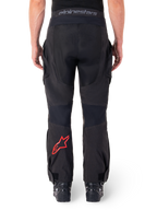 Alpinestars Hyde XT Drystar® Pants, pantaloni da moto adventure, nero con logo a stella rosso sulla parte inferiore della gamba, vista posteriore, design enduro sopra lo stivale con pannelli in tessuto resistente e fascia in vita con marchio
