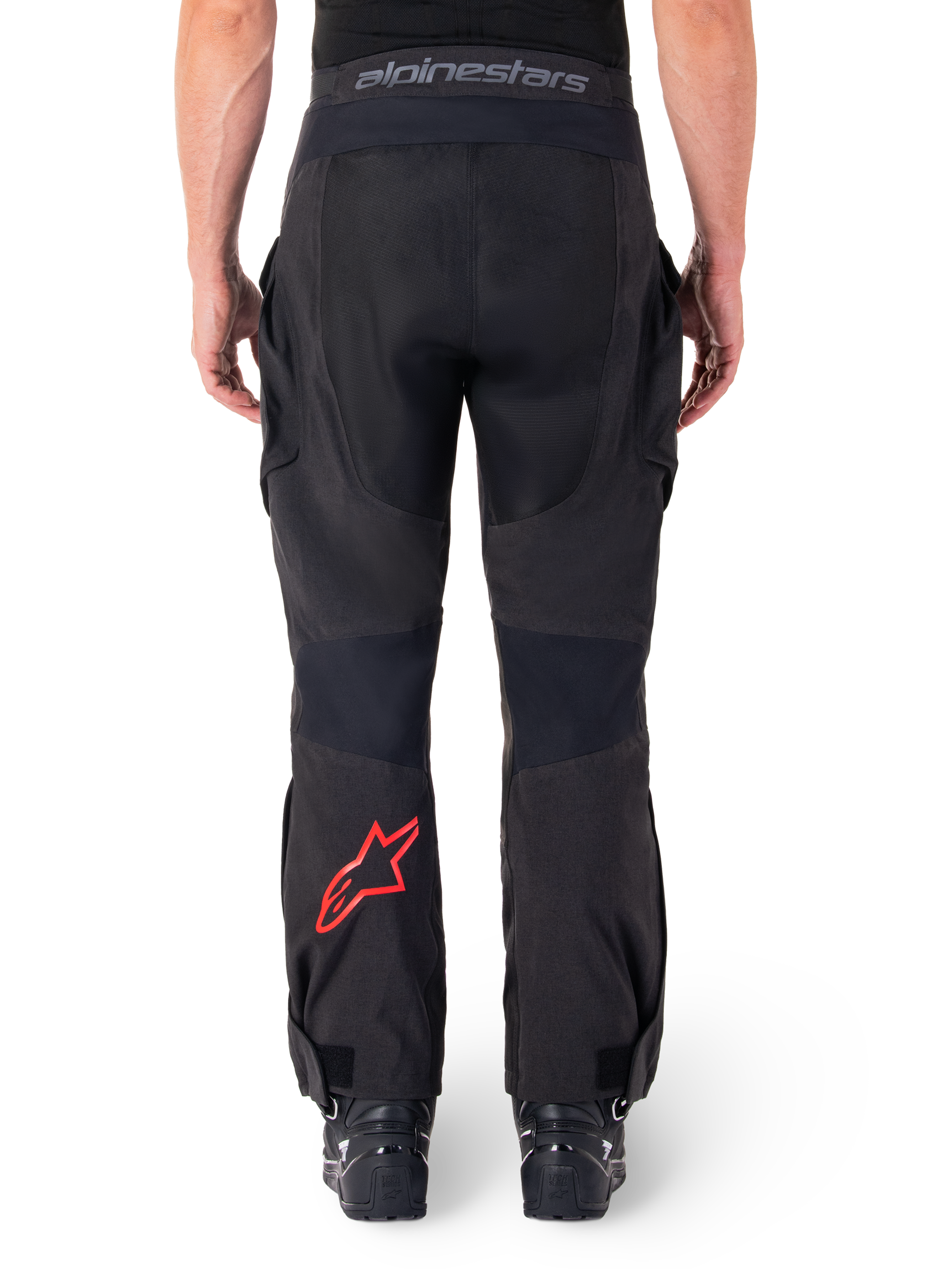 Alpinestars Hyde XT Drystar® Pants, pantaloni da moto adventure, nero con logo a stella rosso sulla parte inferiore della gamba, vista posteriore, design enduro sopra lo stivale con pannelli in tessuto resistente e fascia in vita con marchio